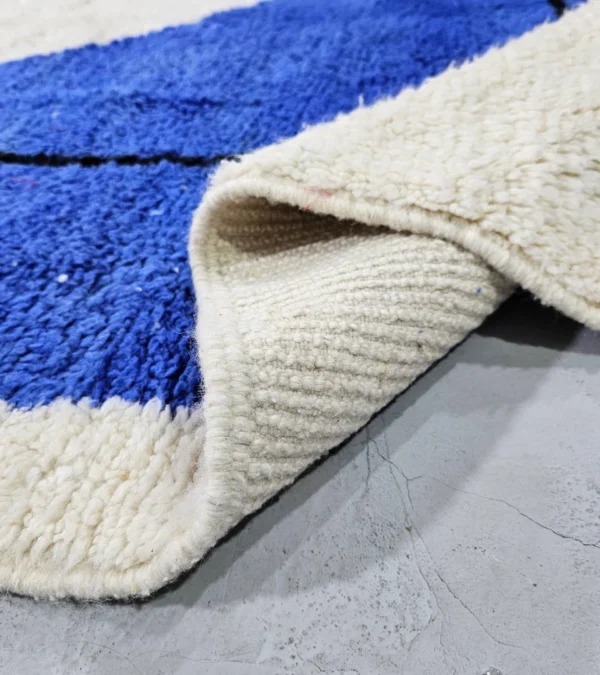 Detailed View of Handmade Moroccan wool rug with blue and mustard abstract design and black outline