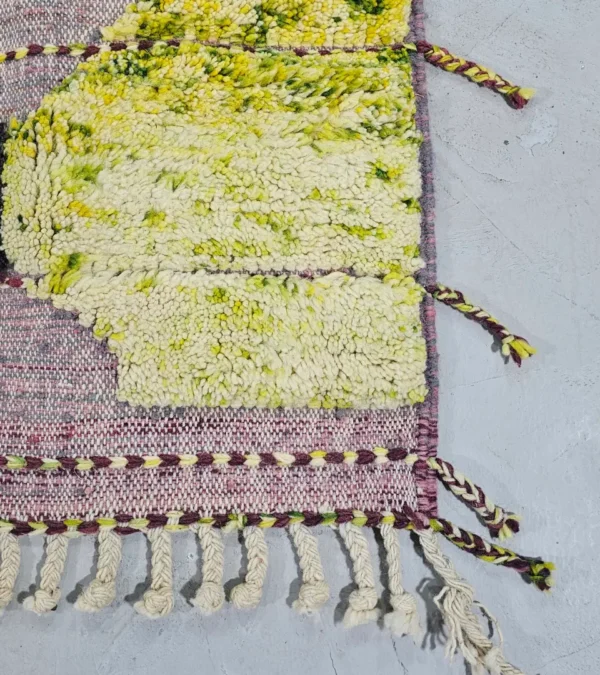 Detailed View of Nayla handmade Azilal wool rug with a bohemian geometric patchwork design in multiple colors including purple, yellow, gray, black, cream, brown, and green