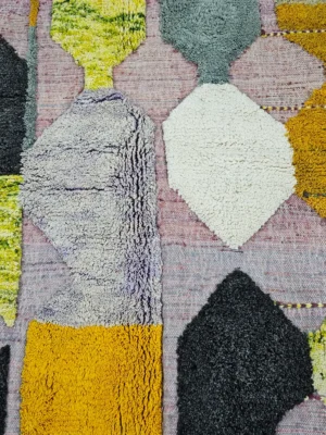 Detailed View of Nayla handmade Azilal wool rug with a bohemian geometric patchwork design in multiple colors including purple, yellow, gray, black, cream, brown, and green