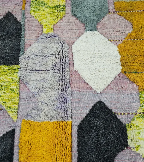 Detailed View of Nayla handmade Azilal wool rug with a bohemian geometric patchwork design in multiple colors including purple, yellow, gray, black, cream, brown, and green