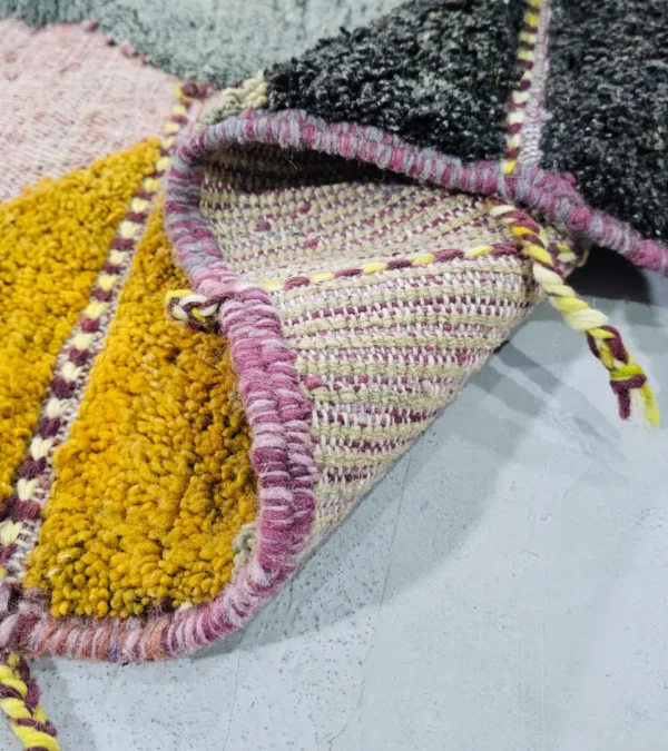Detailed View of Nayla handmade Azilal wool rug with a bohemian geometric patchwork design in multiple colors including purple, yellow, gray, black, cream, brown, and green