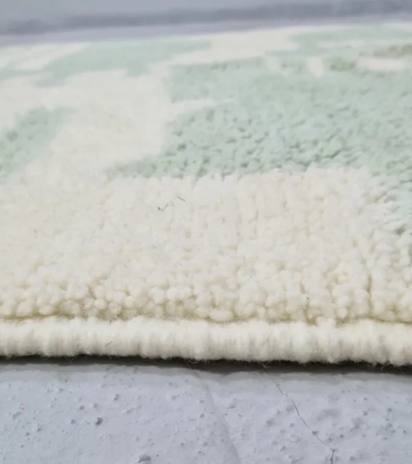 Zoomed In View of Handmade Moroccan rug with a modern abstract interlocking geometric design in neon green and off-white