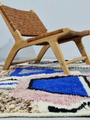 Handmade Moroccan wool rug with an abstract sketch design in pink, blue, brown, black, and off-white in room