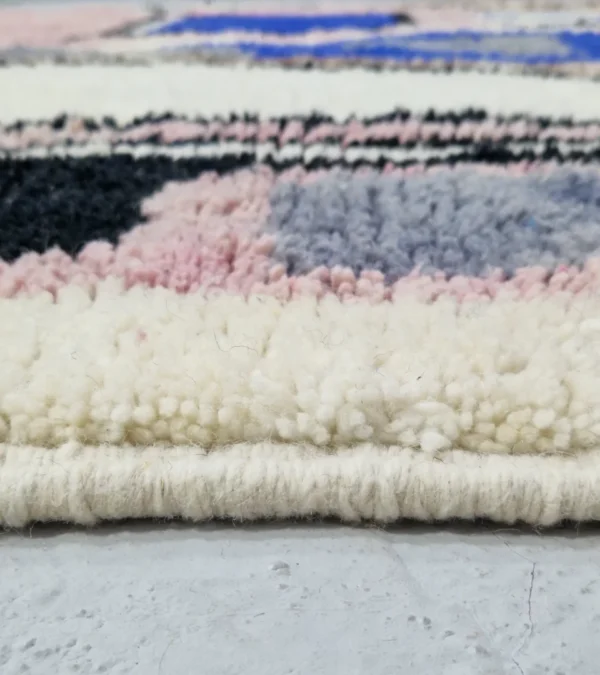 Zoomed In View of Handmade Moroccan wool rug with an abstract sketch design in pink, blue, brown, black, and off-white
