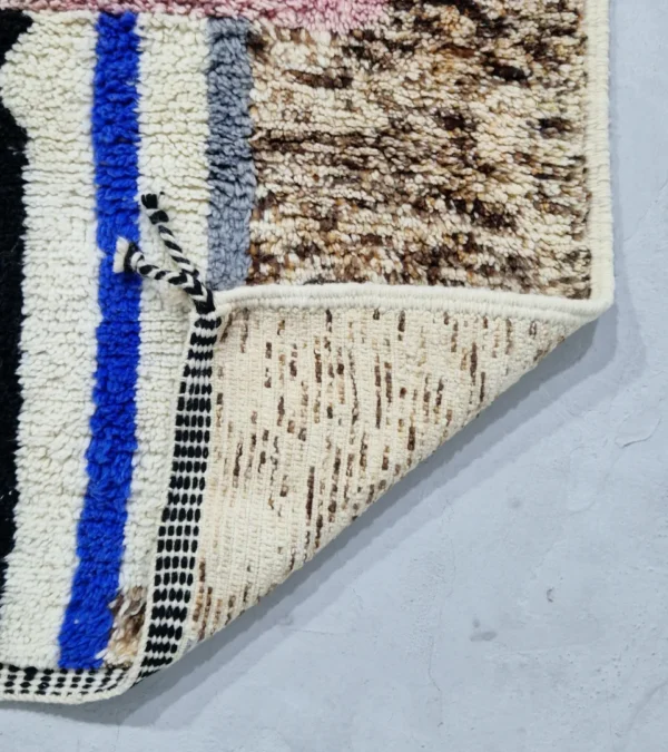 Detailed View of Handmade Moroccan wool rug with an abstract sketch design in pink, blue, brown, black, and off-white