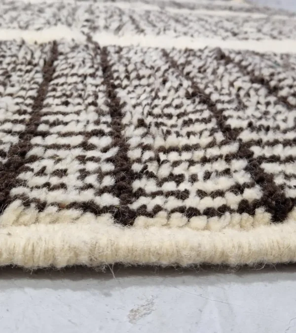 Zoomed In View of Riad handmade Moroccan wool rug with an intricate black and ivory textured design