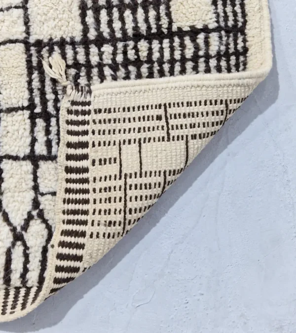 Detailed View of Riad handmade Moroccan wool rug with an intricate black and ivory textured design