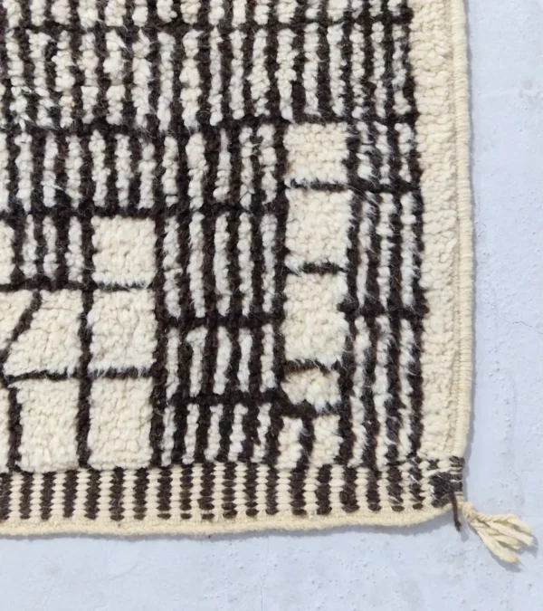 Detailed View of Riad handmade Moroccan wool rug with an intricate black and ivory textured design