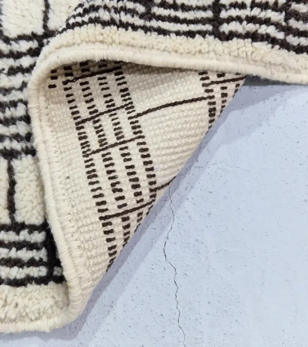 Detailed View of Riad handmade Moroccan wool rug with an intricate black and ivory textured design