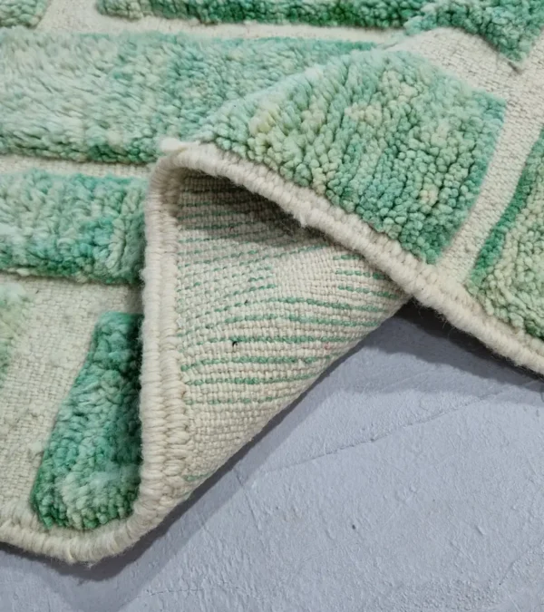 Detailed View of Ruby handmade Moroccan wool rug with a textured, raised abstract design in green and ivory