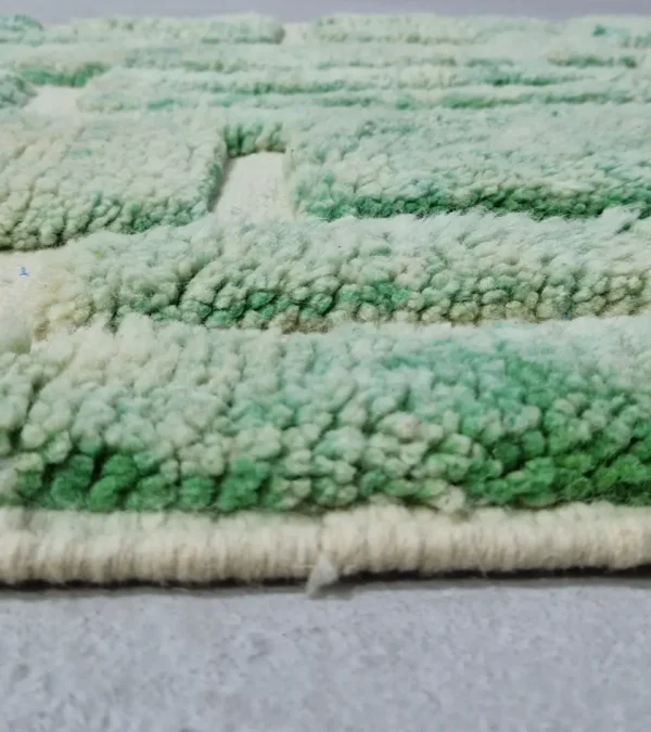 Zoomed In View of Ruby handmade Moroccan wool rug with a textured, raised abstract design in green and ivory