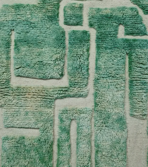 Detailed View of Ruby handmade Moroccan wool rug with a textured, raised abstract design in green and ivory