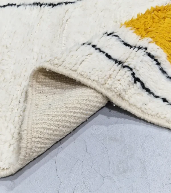 Detailed View of Salma handmade Azilal wool rug with a minimalist geometric design featuring a yellow triangle, teal rectangle, and burgundy rectangle on an ivory background