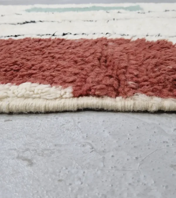 Zoomed In View of Salma handmade Azilal wool rug with a minimalist geometric design featuring a yellow triangle, teal rectangle, and burgundy rectangle on an ivory background