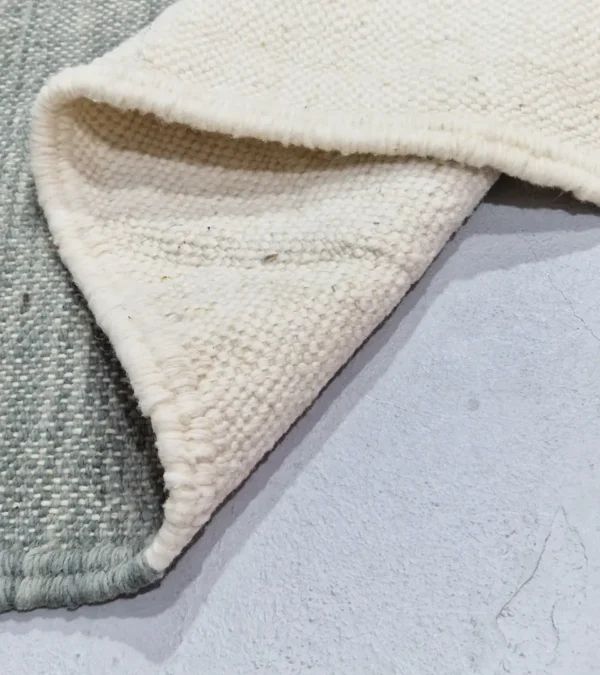 Detailed View of Sana handmade Kilim flatweave wool rug with color blocks in off-white, teal, and beige, with yellow trapezoids