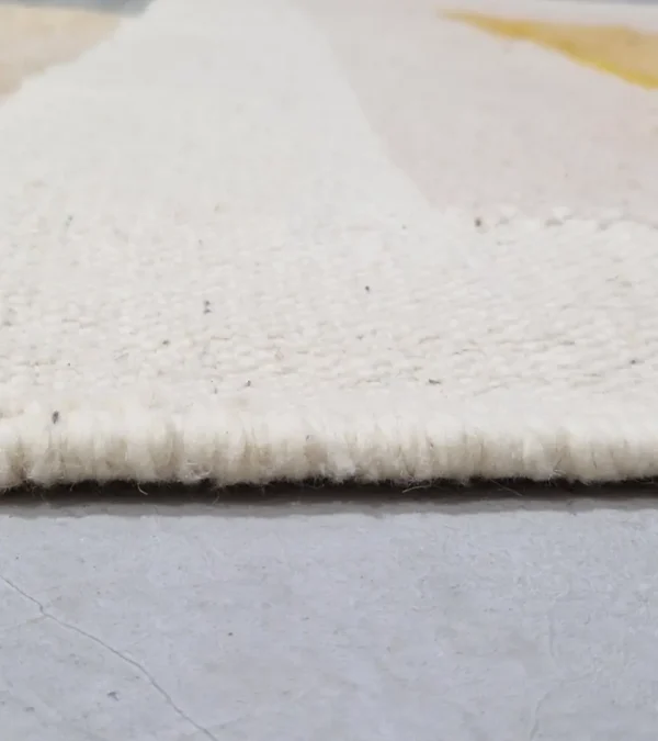 Zoomed In View of Sana handmade Kilim flatweave wool rug with color blocks in off-white, teal, and beige, with yellow trapezoids