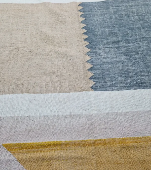 Detailed View of Sana handmade Kilim flatweave wool rug with color blocks in off-white, teal, and beige, with yellow trapezoids