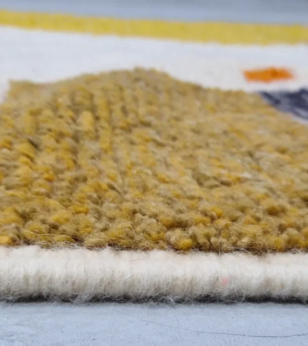 Zoomed In View of Sanaa handmade Beni Ourain wool rug with a contemporary abstract design in multicolor hues including lavender, grayish-green, mustard yellow, dark teal, and golden brown