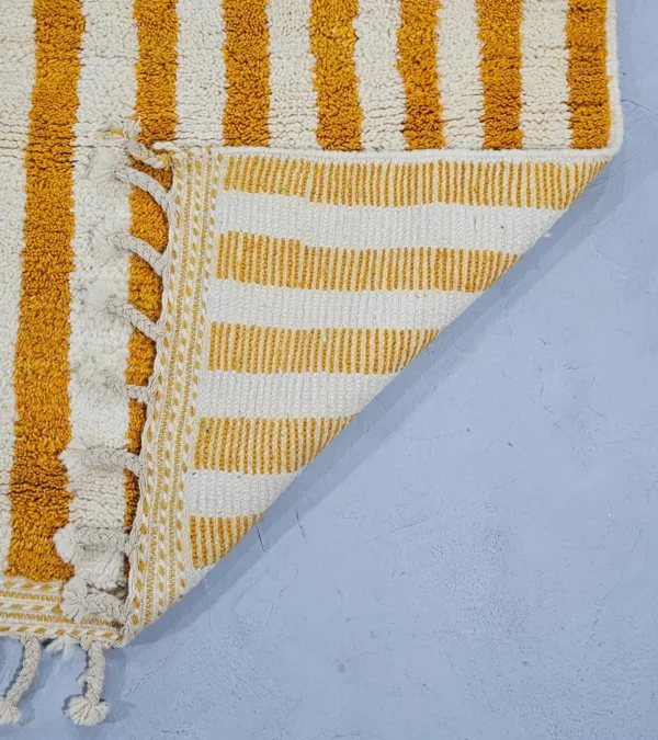 Detailed View of Sara handmade Beni Ourain wool rug with a modern striped and abstract design in yellow and ivory