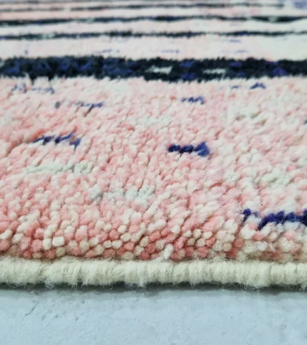 Zoomed In View of Handmade Moroccan wool rug with an abstract geometric design in pink, blue, and black