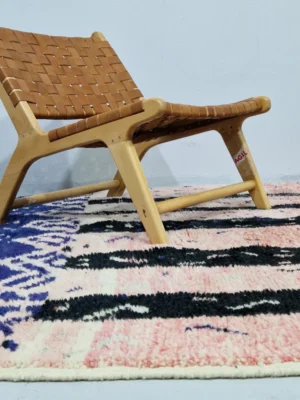Handmade Moroccan wool rug with an abstract geometric design in pink, blue, and black in room