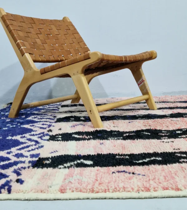 Handmade Moroccan wool rug with an abstract geometric design in pink, blue, and black in room
