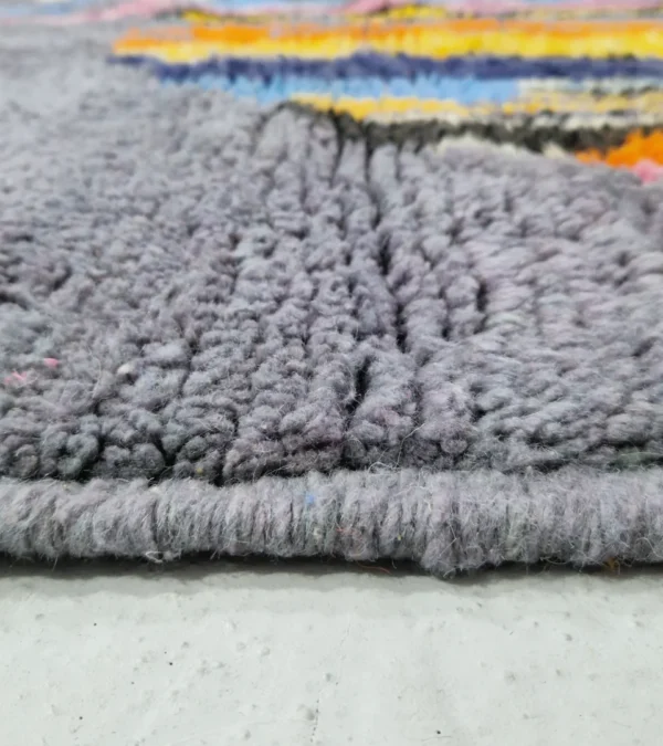 Zoomed In View of Handmade Moroccan wool rug with an abstract skyline design in multi-color on a gray background