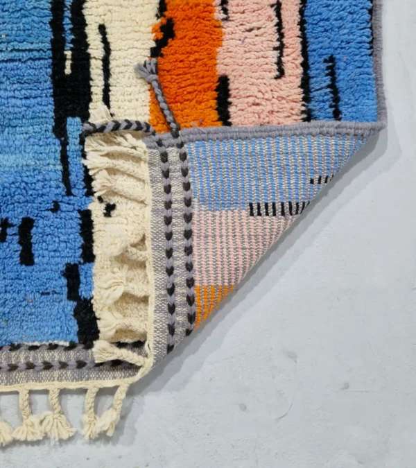 Detailed View of Handmade Moroccan wool rug with an abstract skyline design in multi-color on a gray background