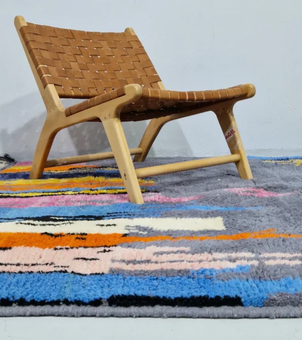 Handmade Moroccan wool rug with an abstract skyline design in multi-color on a gray background in room
