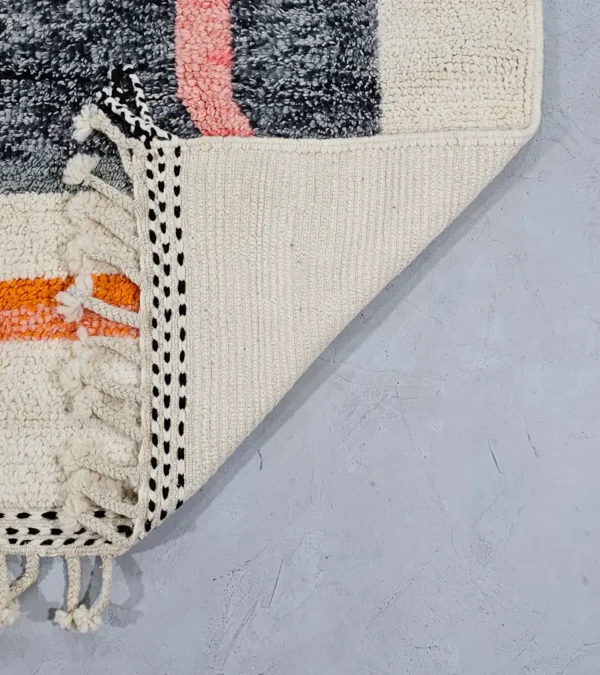 Detailed View of Soraya handmade Beni Ourain wool rug with a minimalist geometric design in dark gray, burnt orange, and bright blue on an ivory background