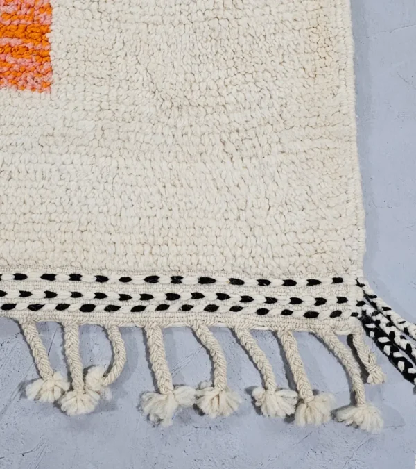 Detailed View of Soraya handmade Beni Ourain wool rug with a minimalist geometric design in dark gray, burnt orange, and bright blue on an ivory background