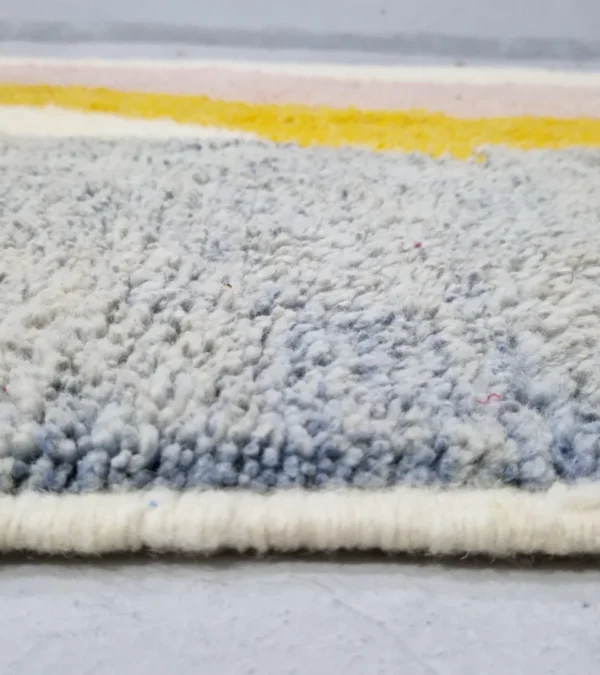Zoomed In View of Handmade Moroccan plush wool rug with a modern cloud-like abstract design in muted pink, yellow, and gray