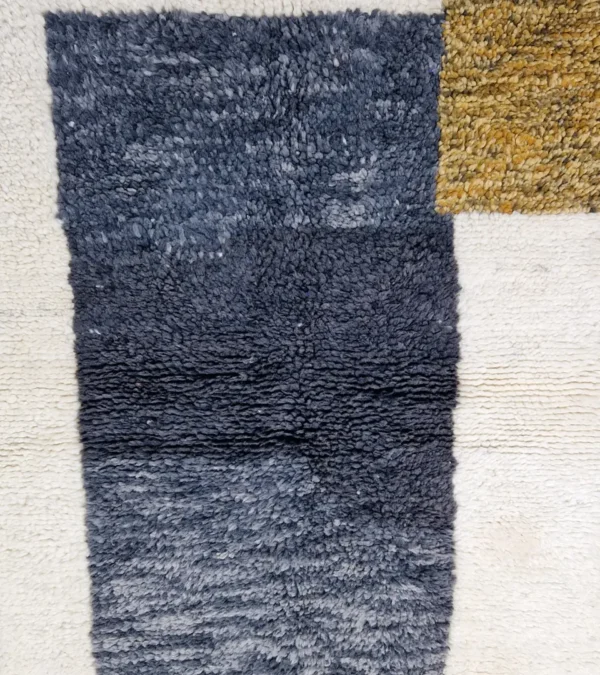 Detailed View of Yara handmade Beni Ourain wool rug with a modern geometric pattern and tassel fringe in charcoal gray, mustard yellow-brown, and ivory