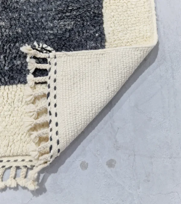 Detailed View of Yara handmade Beni Ourain wool rug with a modern geometric pattern and tassel fringe in charcoal gray, mustard yellow-brown, and ivory