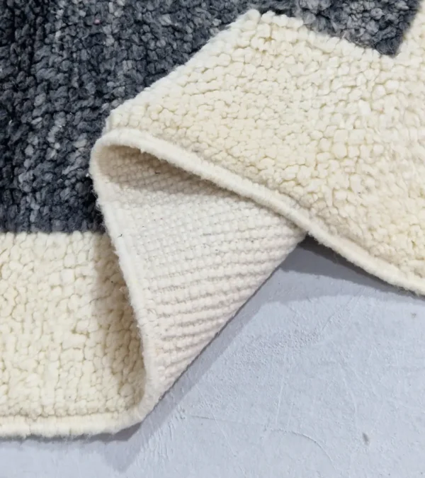Detailed View of Yara handmade Beni Ourain wool rug with a modern geometric pattern and tassel fringe in charcoal gray, mustard yellow-brown, and ivory
