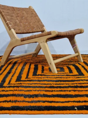 Handmade Moroccan wool rug with orange and navy concentric square stripes in room