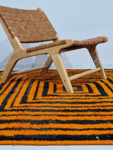 Handmade Moroccan wool rug with orange and navy concentric square stripes in room