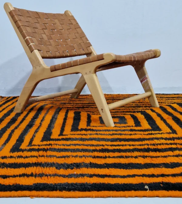 Handmade Moroccan wool rug with orange and navy concentric square stripes in room