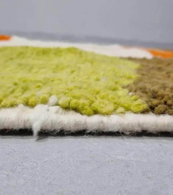 Zoomed In View of Zera handmade Beni Ourain wool rug with a contemporary abstract design in multicolor hues of green, orange, and brown