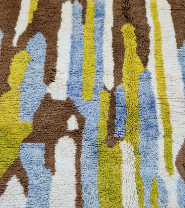 Detailed View of Zola handmade Beni Ourain wool rug with an abstract design of vertical white, blue, and green shapes on a brown background