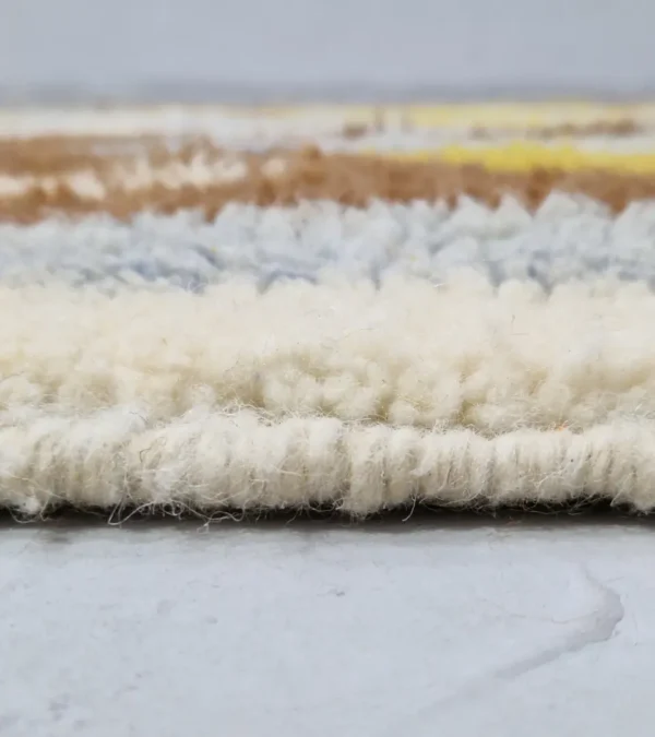 Zoomed In View of Zola handmade Beni Ourain wool rug with an abstract design of vertical white, blue, and green shapes on a brown background