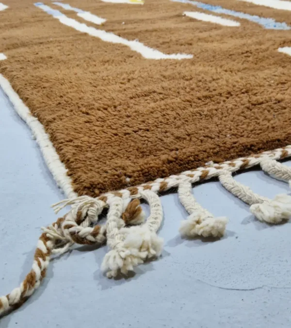 Detailed View of Zola handmade Beni Ourain wool rug with an abstract design of vertical white, blue, and green shapes on a brown background