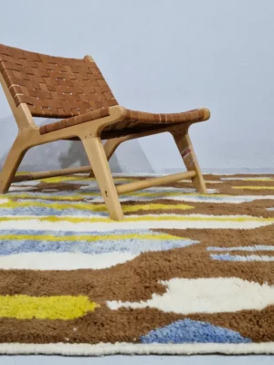 Zola handmade Beni Ourain wool rug with an abstract design of vertical white, blue, and green shapes on a brown background in room