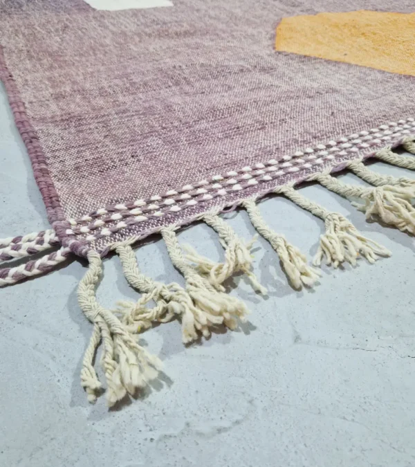 Detailed View of Zola handmade Kilim flatweave wool rug with a purple background and white and yellow geometric shapes