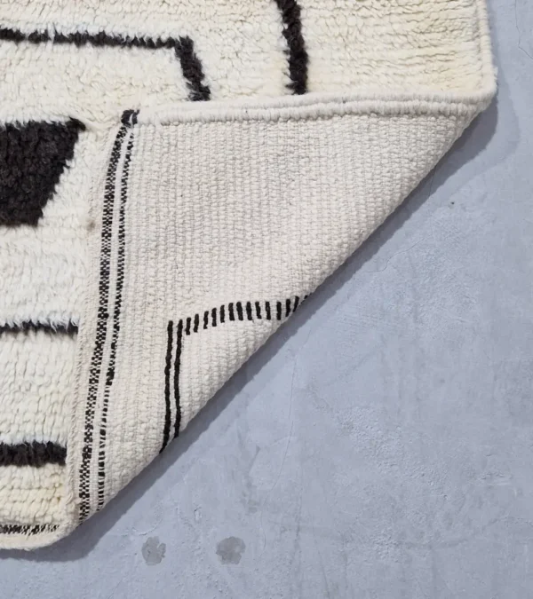 Detailed View of Zola handmade Beni Ourain wool rug with a minimalist design of bold black lines on an ivory background