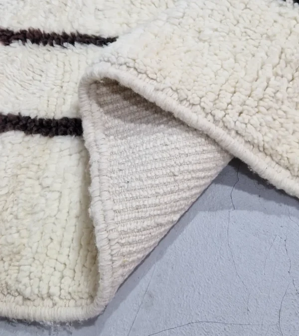 Detailed View of Zola handmade Beni Ourain wool rug with a minimalist design of bold black lines on an ivory background