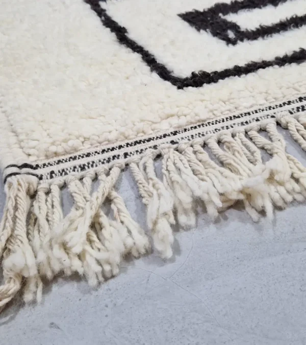 Detailed View of Zola handmade Beni Ourain wool rug with a minimalist design of bold black lines on an ivory background