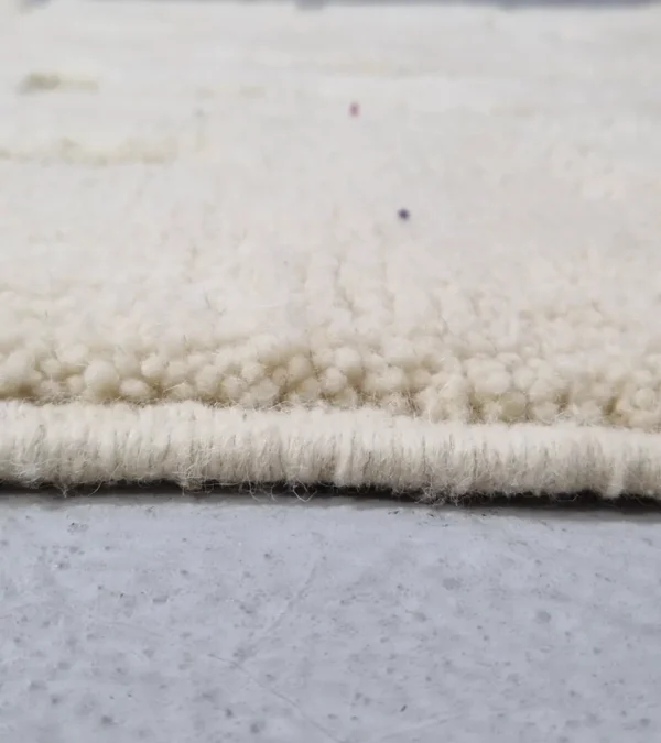 Zoomed In View of Zuri handmade Beni Ourain wool rug with an abstract high-low pile design on a neutral ivory background