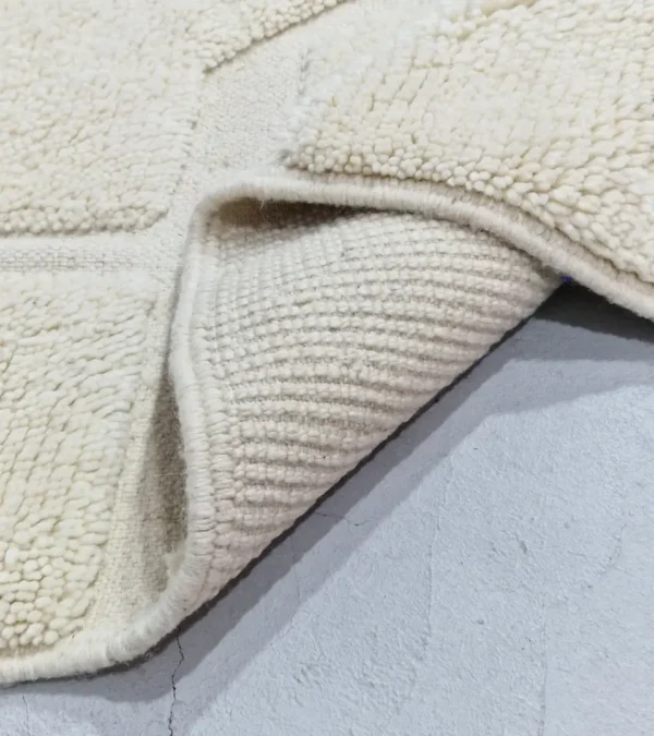 Detailed View of Zuri handmade Beni Ourain wool rug with an abstract high-low pile design on a neutral ivory background