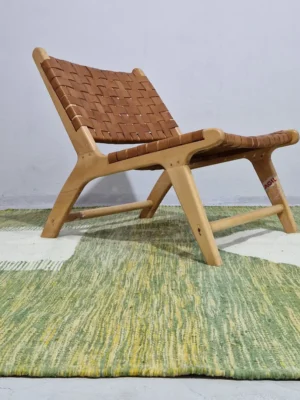 Zuri handmade Kilim flatweave rug with a minimalist textured design and geometric shapes on a green background in room